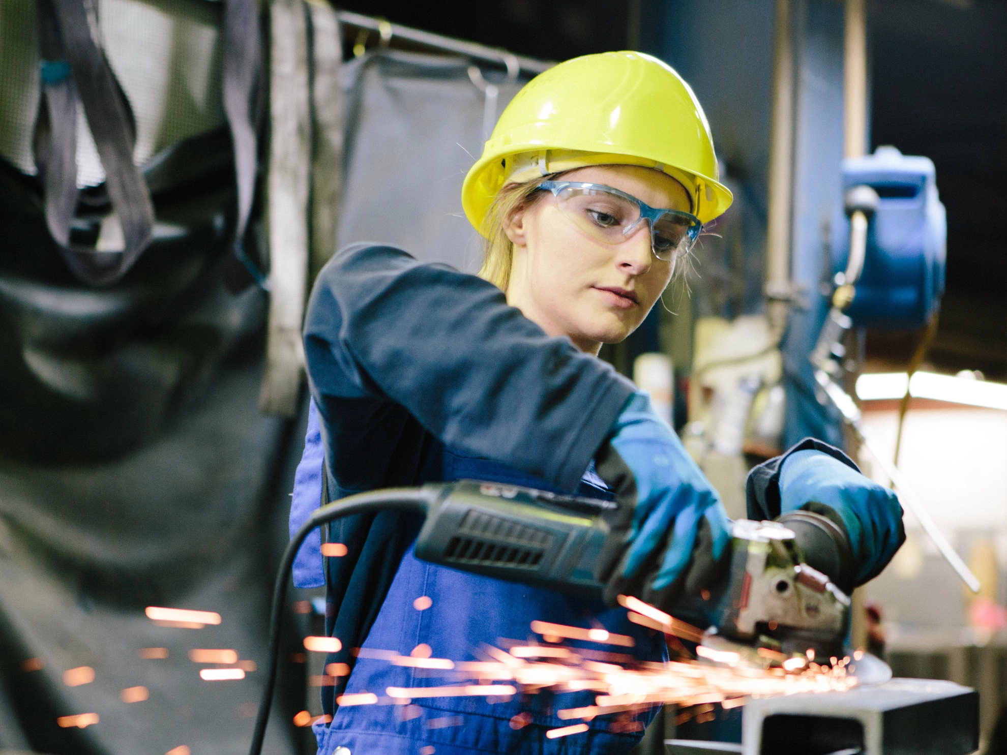 Junge Auszubildende schleift Schweißnähte in einer Werkstatt