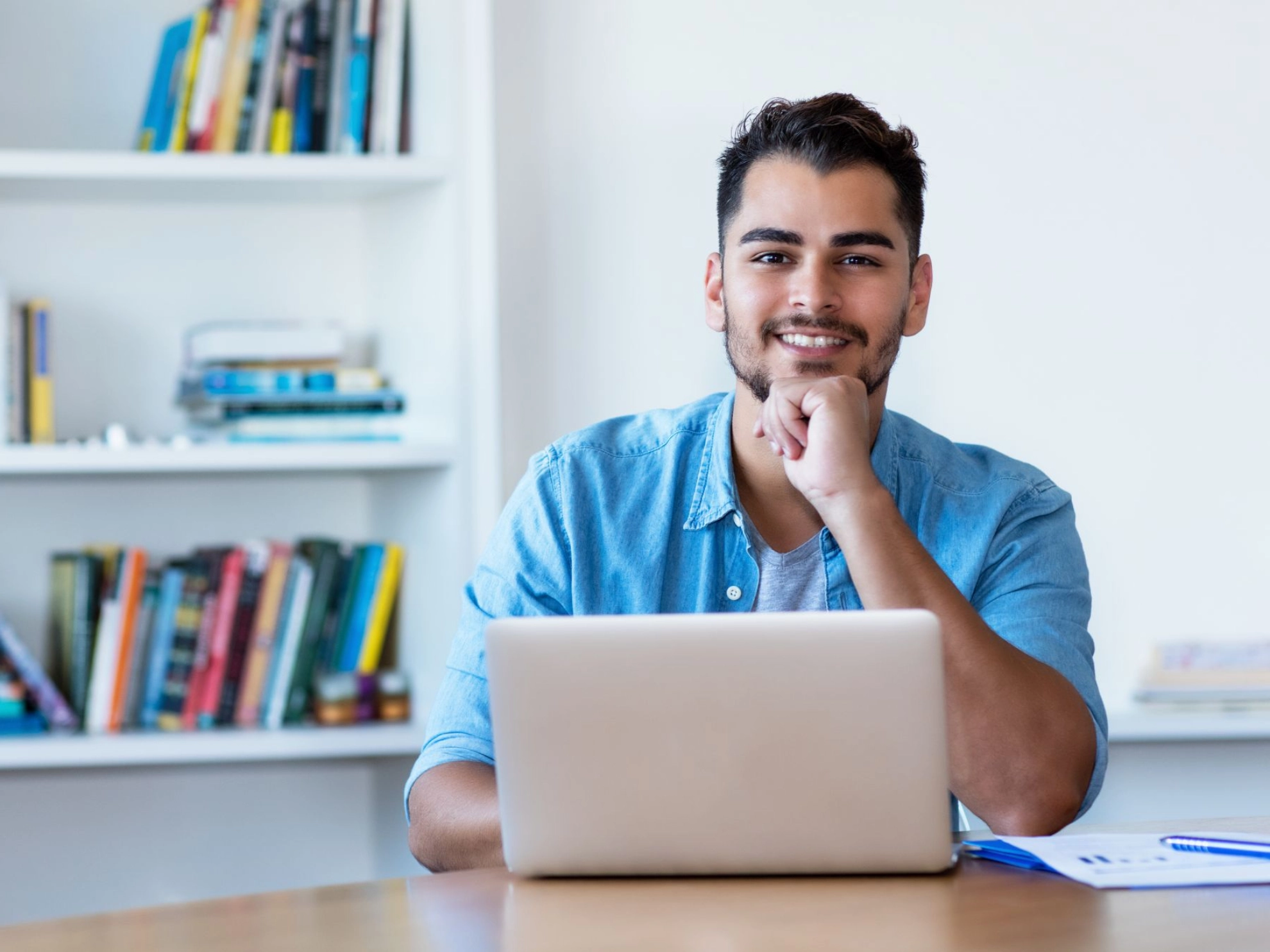 junger Mann sitzt mit einem Laptop zu Hause am Tisch